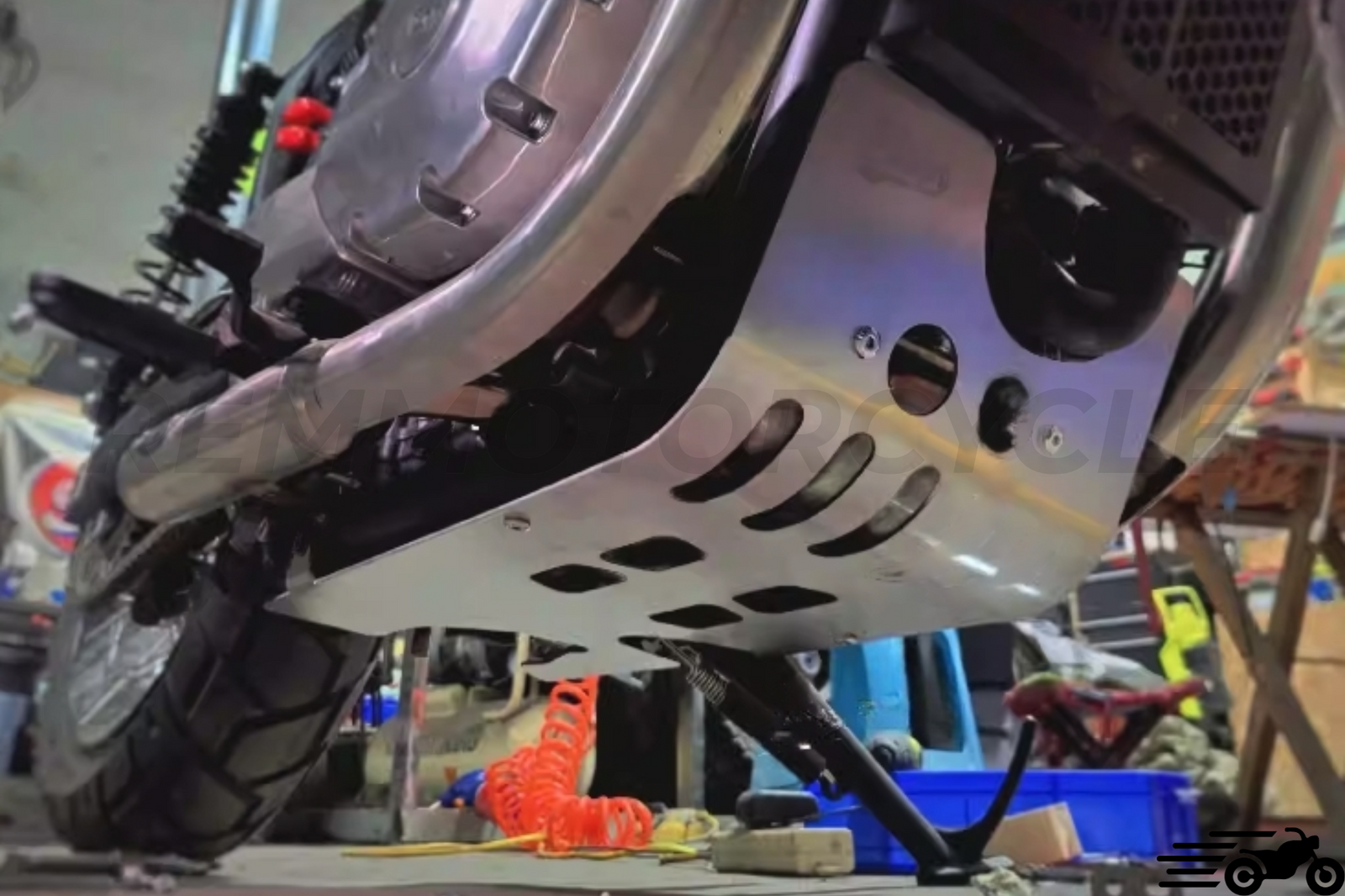 Close-up view of a silver aluminum scrambler engine guard installed on a motorcycle, featuring several openings for engine protection.